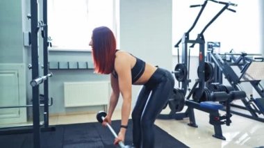 Fitness kadını ve erkek halterli antrenman. Modern spor salonu geçmişi ve ağırlık kaldıran bir çift. Kamera geri gider.