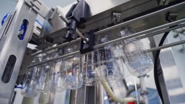 Konveyör hattında asılı duran boş plastik şişeler. Şişe üretim hattı. Modern süt fabrikasındaki sıvı için plastik şişelerin altından görüntüle.
