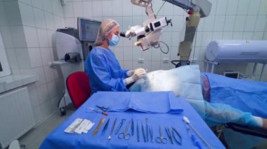 Uzman, mikroskopla göz ameliyatı yapıyor. Tıbbi üniformalı kadın doktor hastanede göz ameliyatı sırasında mikroskop kullanır..