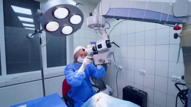 女眼科医生准备用显微镜对眼睛进行手术 医生开始在私家诊所治疗病人的眼睛 — 图库视频影像
