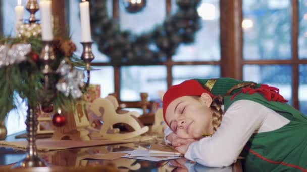 クリスマスだ 自己のテーブルの中で寝ている 美しいです自己目覚め後に彼女の睡眠で装飾された部屋でお祝いのテーブルの背景 — ストック動画