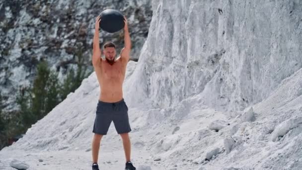 Hombre Musculoso Concentrado Haciendo Ejercicio Con Bola Negra Las Montañas — Vídeo de stock