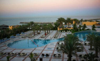 Poolat Oteli. Tatil köyünden yukarıdan bak. Avuçlar ve su. Boş bir otelde günbatımı. Kimse yok..