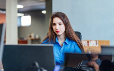 Girişim işi. Modern ofiste bilgisayar üzerinde çalışan bir yazılım geliştiricisi. İş yerinde bir kadın..