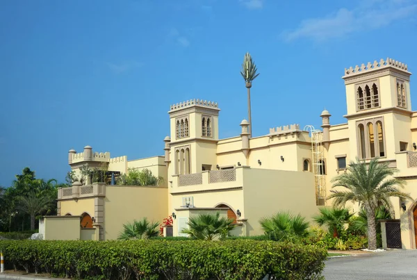 Modern arabic style building. View of the building with palm trees from below.