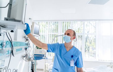 Maskeli doktor. Hastanedeki özel modern oda. Modern tıp yatağı ve modern koğuşta özel bir cihaz..
