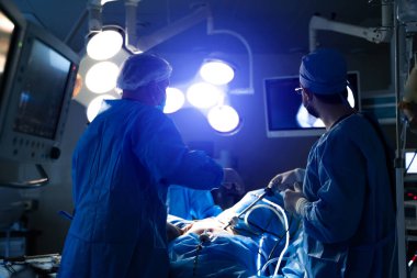 Ameliyathane ve ameliyat devam ediyor. Tıbbi ekip, parlak modern ameliyathanede cerrahi operasyon gerçekleştiriyor.