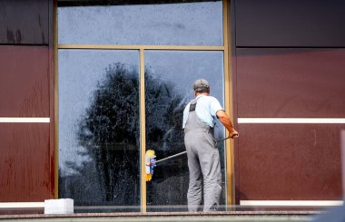 Paçavraları dışarıda yıkanan ev işçisi. Profesyonel temizlik. Büyük panoramik pencereler.