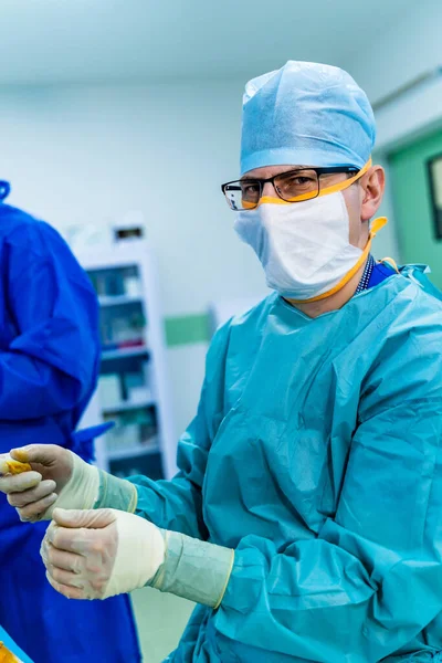 Portrait of a doctor or medical specialist. Vertical portrait. Man in scrubs. Light background with operating room. Closeup.