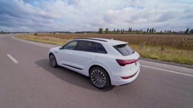 Yolda hafif bir Audi arabasının hava görüntüsü. Beyaz lüks araba otobanda doğal arka planda ilerliyor..