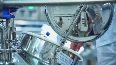 Süt fabrikası içeride. İşçi süt için metal karıştırıcı açar. Süt ve suyu karıştırmak için kase. Ekşi krema ve peynir hazırlıyorum. Peynir üretim süreci. Yakın plan..