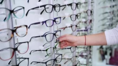 Kürsüde gözlük seçen bir kadın eli. Kadın optik mağazasında yeni gözlük alıyor..
