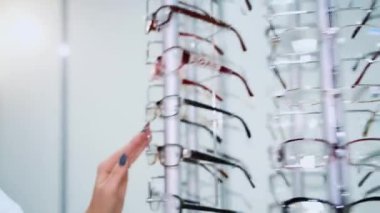 Gözlük dükkanı. Optik mağazasında gözlüklü dur. Kadın eli bardakları seçer..