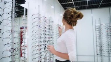Güzel genç bir kadın gözlükçüden yeni bir çift gözlük seçiyor. Görme düzeltmesi. Optik. Oftalmoloji.