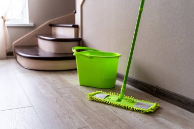 Beyaz duvarın yanında duran yeşil paspas. Temizlik malzemeleri. Yeşil plastik kova. Ev idaresi.