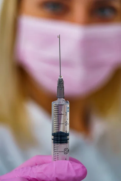 Medicinsk Spruta Handen Rosa Handske Suddig Bakgrund Kvinnans Ansikte Injektionskoncept — Stockfoto