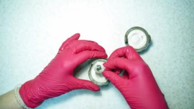 Göz protezi üretiyorum. Doktorun elleri plastik göz protezini temizliyor. Bir teknisyenin elindeki yapay gözü hazırlayın..