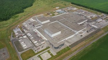 Kamyonlar için park yeri olan büyük bir sanayi merkezinin üst görüntüsü. Doğayla çevrili modern üretim kompleksinin havadan görünüşü. Yavaş çekim kamerası.