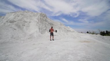 Genç sporcu doğal dağ arka planında ağır halter kaldırıyor. Bir yaz günü, halterle meşgul olan konsantre bir adam..