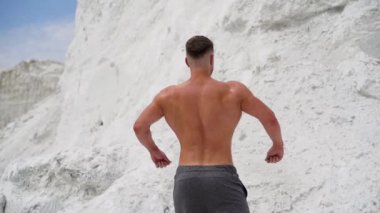Dışarıda kaslı vücutlu bir sporcunun arka görüntüsü. Beyaz dağ arka planında sağlıklı bir vücut geliştirici..