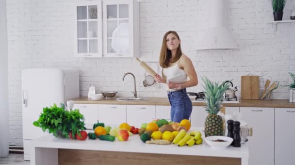 漂亮的女人在厨房里的滚动销 年轻的家庭主妇对厨房用具怒气冲冲 桌上的新鲜有机水果和蔬菜 — 图库视频影像