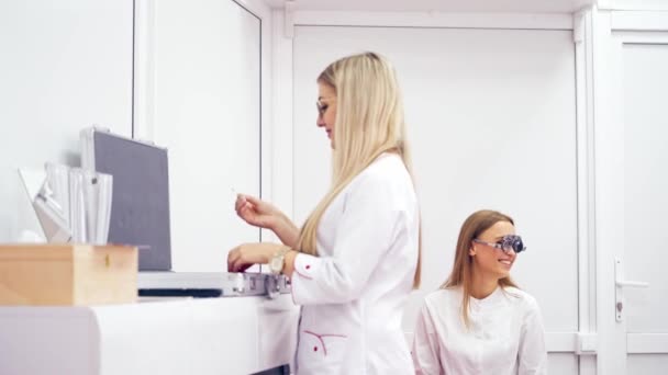 眼科医は 光学機器を使用して 女性にダイオプターを選択します 診療所での患者のための眼鏡レンズの目の検査と選択 — ストック動画