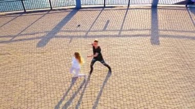 Modern dansçılar sokakta dans ediyor. Şehir yaşam tarzı. Hip-hop nesli. Videodaki kızın ve erkeğin duygusal hareketleri. Kayalık taşlar ve fondü arka planında genç gösterişli bir çift. Hava görüntüsü. Genç güzellik yakışıklı oğlanla dans ediyor.