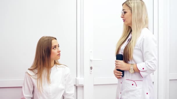 在一位美丽的眼科医生的咨询下 一位年轻的妇女 穿着白衣的有魅力的医生与医院里的女病人交谈 — 图库视频影像
