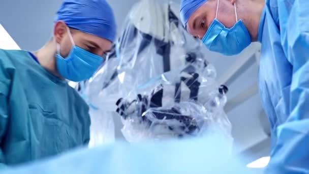 显微镜背景上有身穿蓝色防护服的医学专家 在诊所进行手术的医生 — 图库视频影像