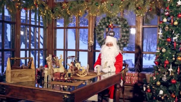 Papai Noel Está Sentado Quarto Especialmente Decorado Mesa Segurando Madeira — Vídeo de Stock