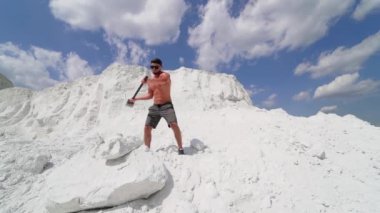 Tepede çekiçli bir sporcu. Yazın beyaz dağda çekiçle antrenman yapan üstsüz bir sporcu. Dışarıda kaslı vücudu olan yakışıklı bir adam..