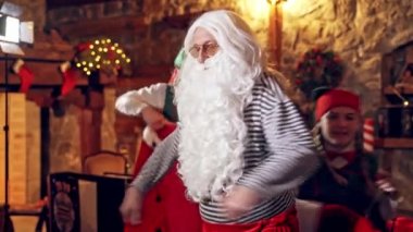 Beyaz sakallı Noel Baba. Elfler yaşlı adamın sabahları Noel Baba kostümünü giymesine yardım eder..