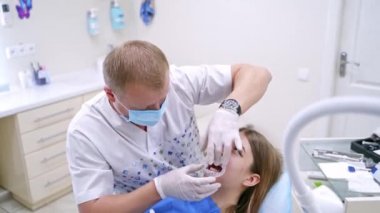 Diş hekiminde dişleri tedavi eden bir diş hekimi. Stomatolog dişleri delmeden önce hastanın ağzına özel bir maske takıyor. Hastanede mesleki diş tedavisi.