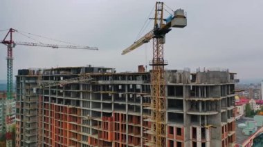 Konut kompleksi inşaatı. Çok katlı bina yapım aşamasında. Vinçler çalışıyor. Hava görünümü.