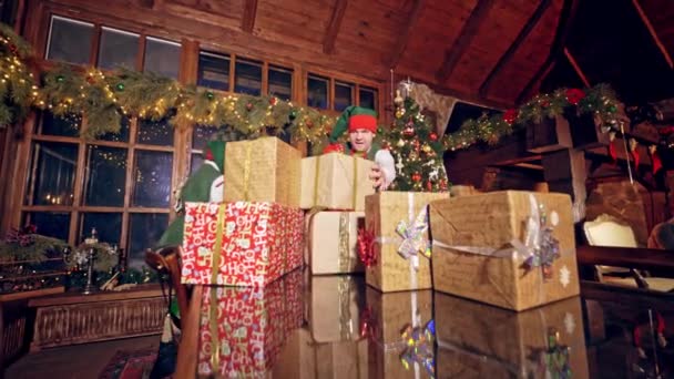 Cadouri Crăciun Masă Doi Elfi Fericiți Punând Cadouri Birou Camera — Videoclip de stoc