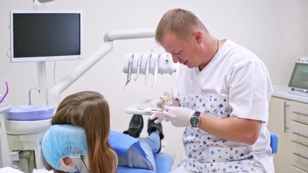 Стоматолог Моделлю Щелепи Пацієнткою Клініці Стоматолог Розмовляє Пацієнткою Використовуючи Штучні — стокове відео
