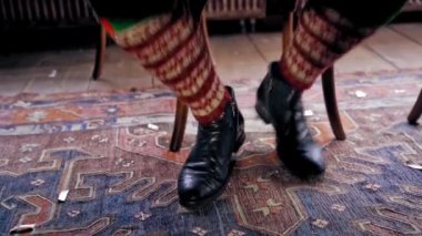 Aç elf sabırsızlıkla Noel masasında ayaklarını yere vuruyor. Yeşil kapüşonlu erkek elf, portakalların önünde şenlik masasında oturuyor. Yeni yıl ve Noel konsepti.