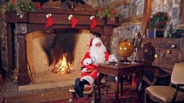 Noel Baba özel dekore edilmiş bir odada oturuyor ve mektuba bir büyüteç ya da silindir ile bakıyor. Noel ve Yeni Yıl konsepti. Mucize zamanı..