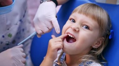 Stomatoloji kürsüsündeki küçük çocuk hasta dişini parmağıyla işaret ediyor. Videoyu kapat. Sağlıklı diş konsepti videosu.