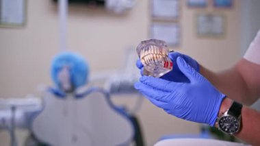 Doktor plastik çene örneğinde ya da diş tedavisinde farklı yöntemler gösteriyor. Modern diş sağlığı kliniği geçmişi. Erkek doktorun ellerinde mavi tıbbi eldiven. Diş Sağlığı ve Diş Sağlığı konsepti videosu.