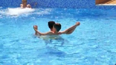 Anne ve çocuk yüzme havuzunda. Açık havada bir kadının yardımıyla havuzda yüzen bir çocuk. Yazın aile tatili.