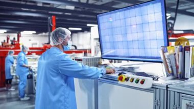 Modern teknolojik olarak gelişmiş bir fabrika. İşçiler endüstriyel fabrikadaki büyük ekranda endüstriyel makinenin işleyişini ayarlıyorlar.