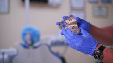 Doktorun elindeki yapay dişler. Diş hekimi çene modelinde nasıl çıkarılacağını ve implant takılacağını gösteriyor. Diş sağlığı kliniği. Yakın plan..
