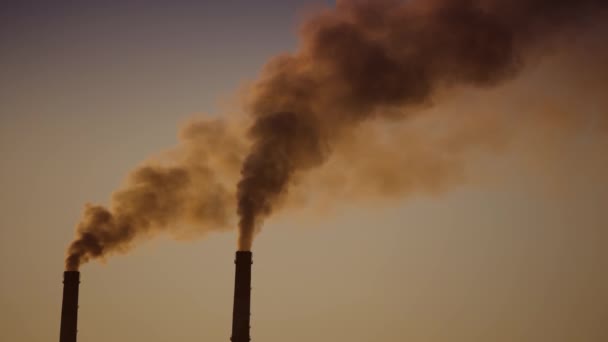 日没時に空気中のパイプからの暗い煙 工業工場の2つの大きなパイプは夕方に化学煙を発生させます 環境汚染 — ストック動画