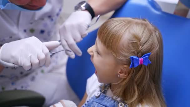 소녀가 의자에 있습니다 아이가 기형학자한테 벌려요 의사가 소녀의 이빨을 합니다 — 비디오