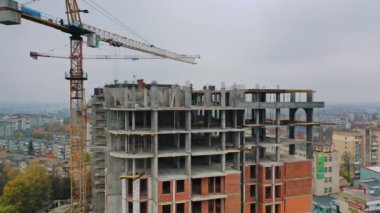 Şehirde yeni bir inşaat alanı. Şehir binasını inşa eden iki büyük vinç. Şehrin arka planında yüksek binalar inşa ediliyor. Manzara. Kameranın yuvarlak hareketi.