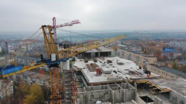 İnşaat alanındaki vinçle yukarıdan bak. Binanın arka planında büyük bir vinç var. Hava görüntüsü. Yavaş çekim.