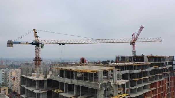 高层建筑的建设过程 在城市的一个大型建筑工地上 工人们在工作起重机的背景下工作 慢动作相机上下左右移动 — 图库视频影像