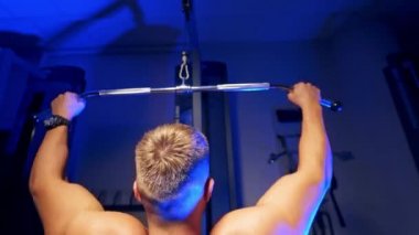 Güçlü atletik adamlar kaslarını şişiriyor. Spor malzemeleriyle antrenman yapıyorum. Vücut geliştiren kaslı biri. Spor salonunda çıplak vücutla egzersiz yapıyor. Spor ve vücut geliştirme konsepti. Arkadan video..
