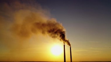 Havada kara duman var. Gün batımında gökyüzünde kimyasal emisyonları olan bitkiden iki boru. Ekolojik sorunlar. Atmosfer tehlikede..